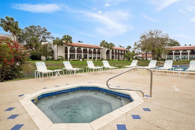 view of pool featuring a lawn, a hot tub, and a patio