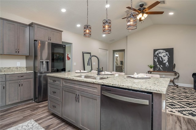 kitchen with dark hardwood / wood-style flooring, lofted ceiling, sink, a kitchen island with sink, and appliances with stainless steel finishes