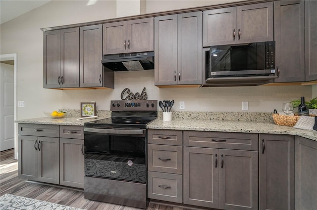 kitchen featuring black electric range oven, light hardwood / wood-style floors, lofted ceiling, and light stone counters