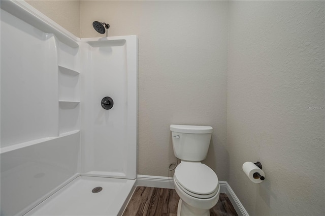 bathroom featuring toilet, a shower, and wood-type flooring