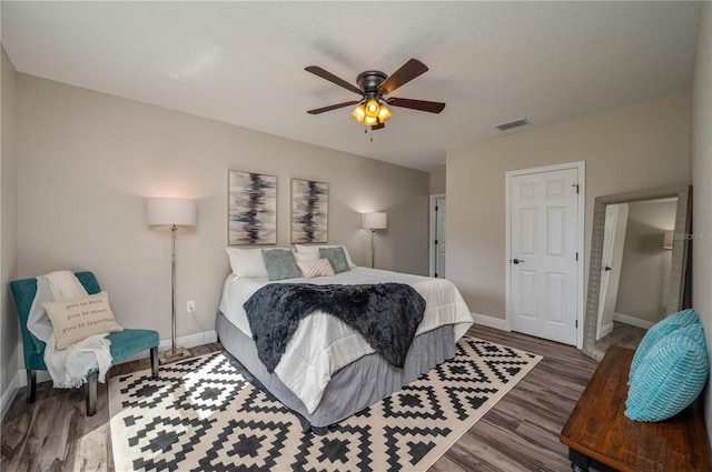 bedroom with ceiling fan, a textured ceiling, and dark hardwood / wood-style flooring