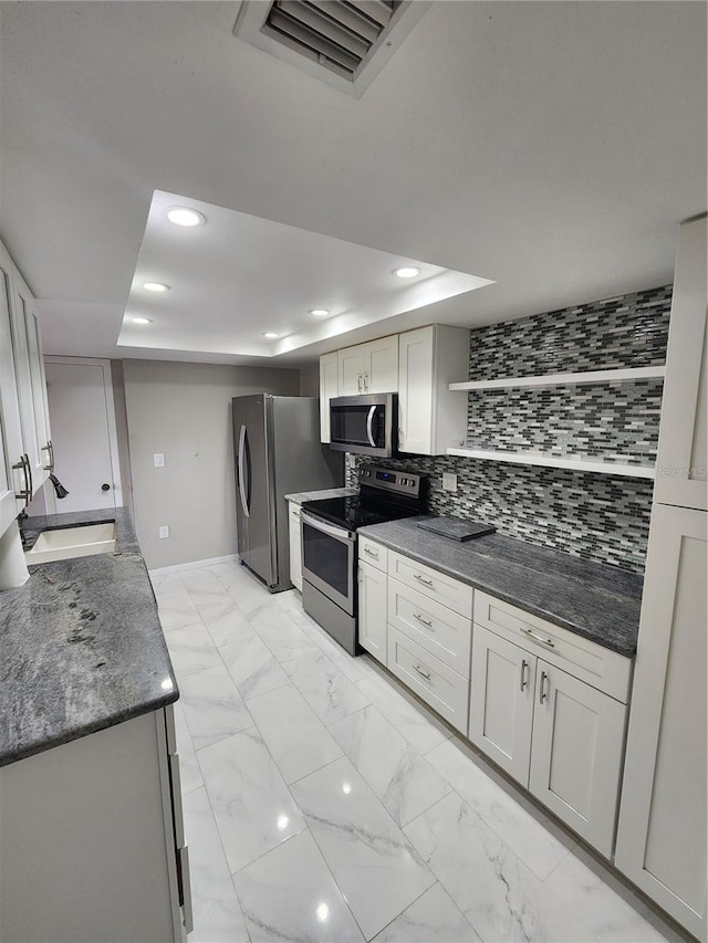 kitchen featuring decorative backsplash, stainless steel appliances, sink, and dark stone counters