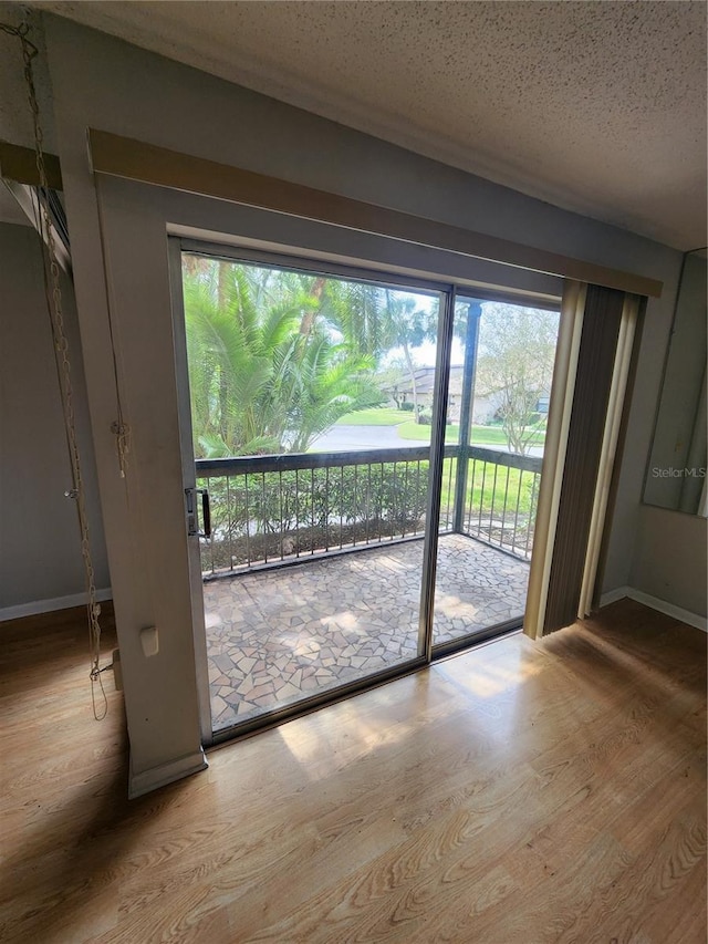 doorway to outside with wood-type flooring, a textured ceiling, and plenty of natural light