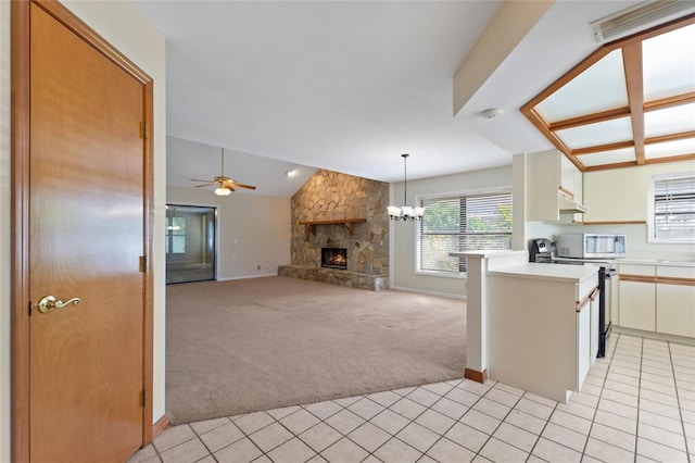 kitchen with lofted ceiling, kitchen peninsula, hanging light fixtures, light colored carpet, and a fireplace