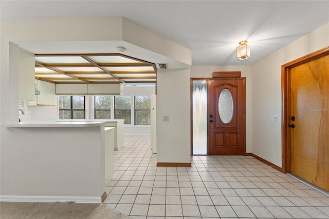 entryway featuring beam ceiling, coffered ceiling, and light tile patterned floors