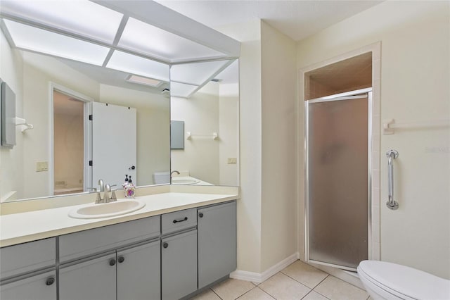 bathroom featuring toilet, tile patterned flooring, vanity, and a shower with door