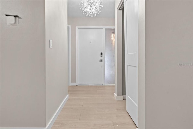 corridor with a chandelier and light wood-type flooring