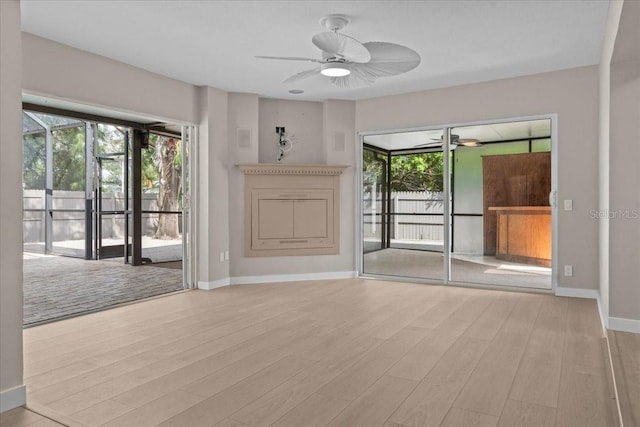 unfurnished living room with ceiling fan, light hardwood / wood-style flooring, and a fireplace