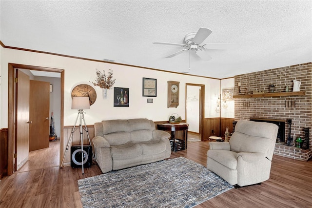 living room featuring ceiling fan, wooden walls, a textured ceiling, and wood-type flooring