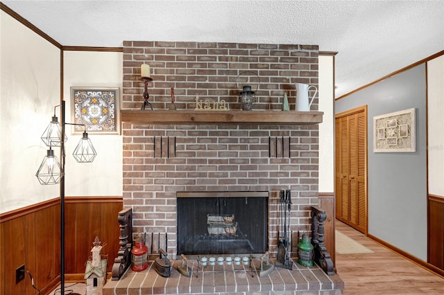 interior details featuring a brick fireplace, wooden walls, crown molding, and hardwood / wood-style flooring