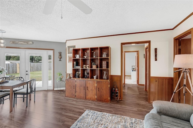 living room with dark wood-type flooring, a textured ceiling, wood walls, french doors, and ceiling fan