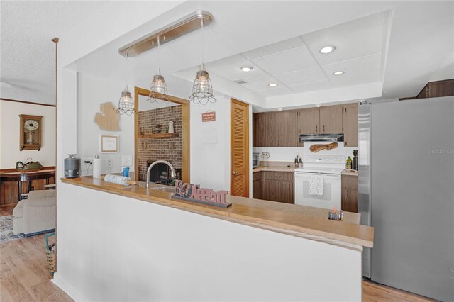 kitchen with kitchen peninsula, light hardwood / wood-style flooring, hanging light fixtures, stainless steel fridge, and electric range