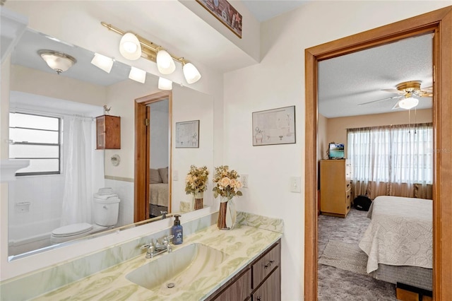 full bathroom with a textured ceiling, ceiling fan, toilet, shower / bath combination with curtain, and vanity