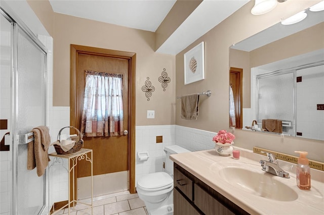 bathroom with toilet, tile walls, a shower with door, tile patterned floors, and vanity