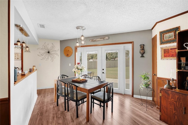 dining area featuring french doors, a textured ceiling, and light wood-type flooring