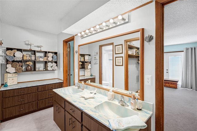 bathroom with a textured ceiling, vanity, and toilet