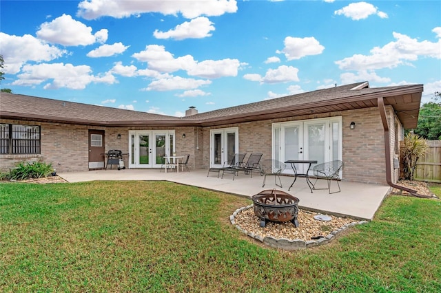 rear view of property featuring a fire pit, french doors, a yard, and a patio