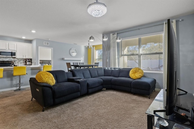 carpeted living room with a chandelier