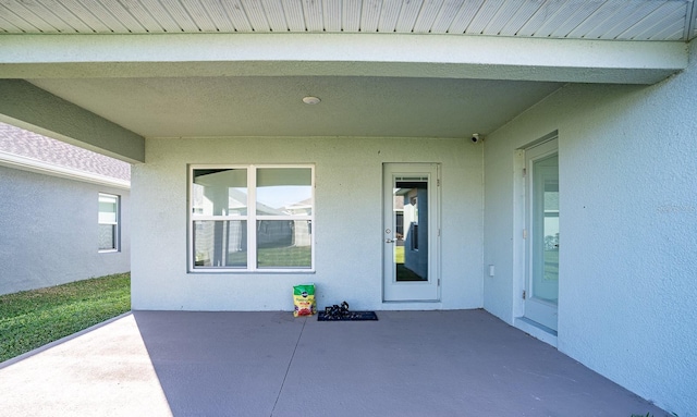 view of exterior entry with a patio area