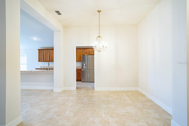 unfurnished room with sink and a notable chandelier
