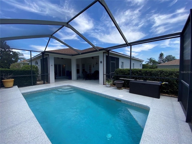 view of swimming pool with a patio area, ceiling fan, and glass enclosure