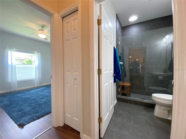 bathroom featuring a shower with door, tile patterned floors, toilet, and ceiling fan