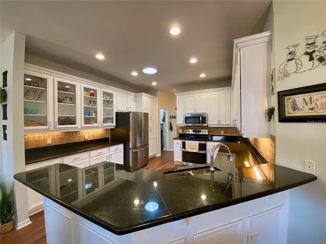 kitchen featuring decorative backsplash, dark wood-type flooring, kitchen peninsula, stainless steel appliances, and white cabinets