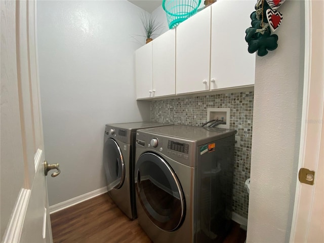 clothes washing area with dark wood-type flooring, washer and dryer, and cabinets