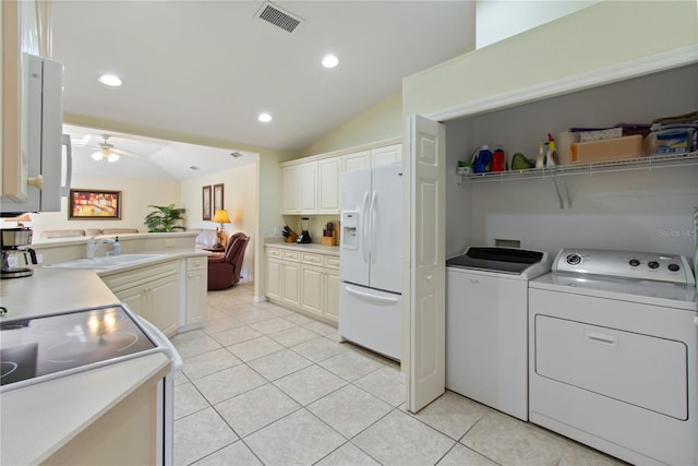 kitchen with light tile patterned floors, white refrigerator with ice dispenser, washing machine and clothes dryer, and vaulted ceiling