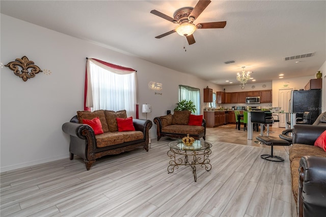 living room featuring light wood-type flooring and ceiling fan with notable chandelier