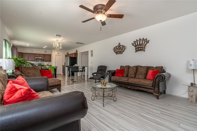 living room with light hardwood / wood-style flooring and ceiling fan with notable chandelier