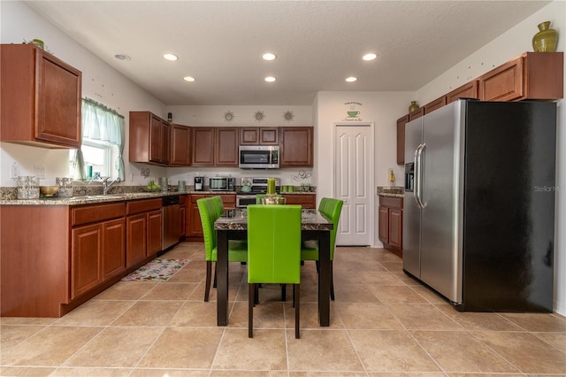 kitchen with appliances with stainless steel finishes, sink, a textured ceiling, a center island, and light tile patterned floors