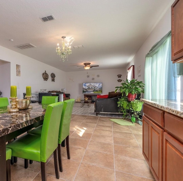 dining area featuring light tile patterned floors and ceiling fan with notable chandelier