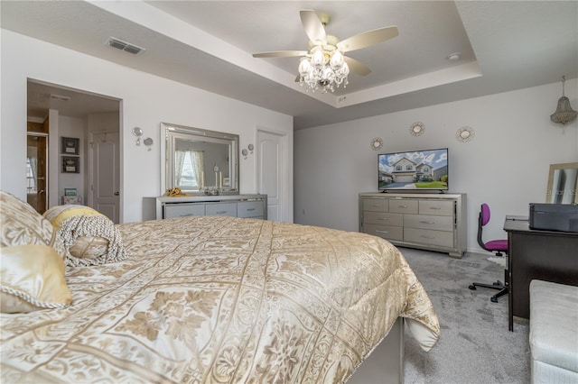 carpeted bedroom with a raised ceiling and ceiling fan