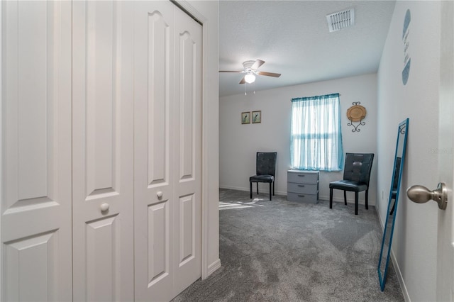 hall featuring dark colored carpet and a textured ceiling