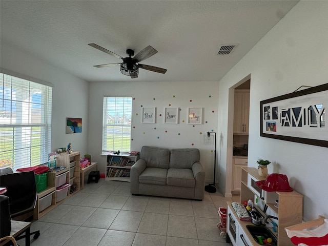 living room with a textured ceiling, ceiling fan, and light tile patterned floors