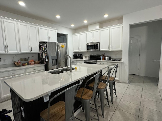 kitchen featuring appliances with stainless steel finishes, sink, an island with sink, white cabinets, and a breakfast bar