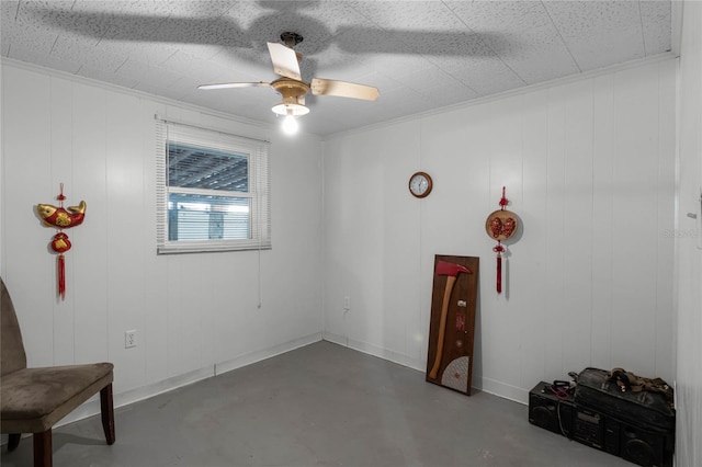 interior space with concrete floors, wood walls, and ceiling fan