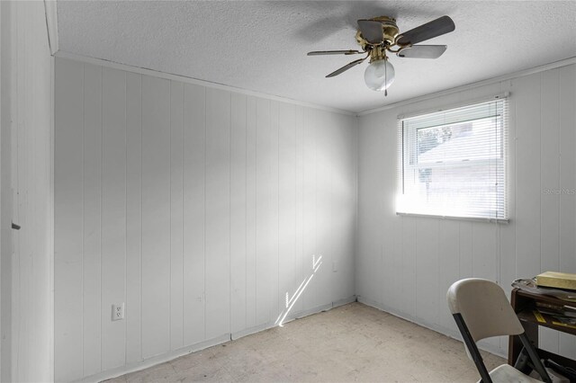 office featuring ceiling fan, a textured ceiling, and wood walls