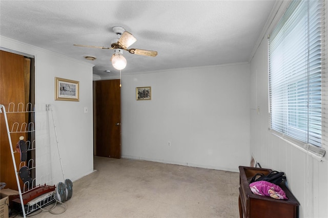 empty room with ornamental molding, a textured ceiling, light carpet, and ceiling fan