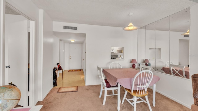 carpeted dining space with a textured ceiling