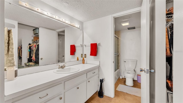 full bathroom with vanity, shower / bath combination with glass door, tile patterned flooring, toilet, and a textured ceiling