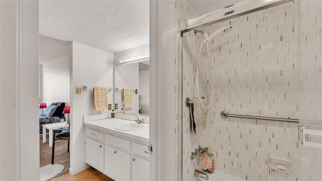 bathroom with vanity, wood-type flooring, a textured ceiling, and tiled shower / bath