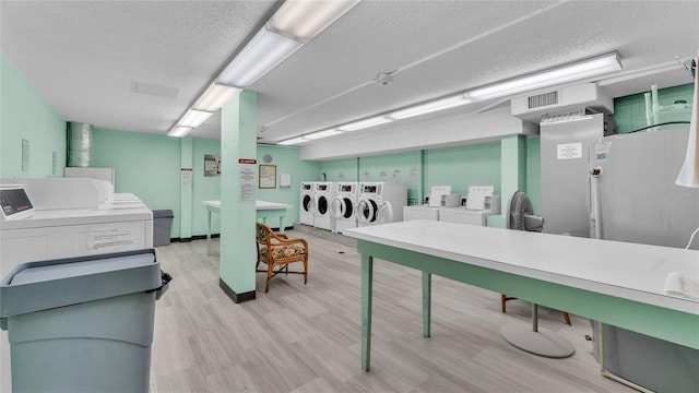 laundry area featuring washing machine and dryer, light hardwood / wood-style floors, and a textured ceiling