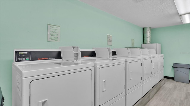 laundry room with a textured ceiling, light hardwood / wood-style flooring, and washing machine and clothes dryer