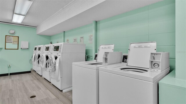 laundry room with light wood-type flooring, independent washer and dryer, and a textured ceiling