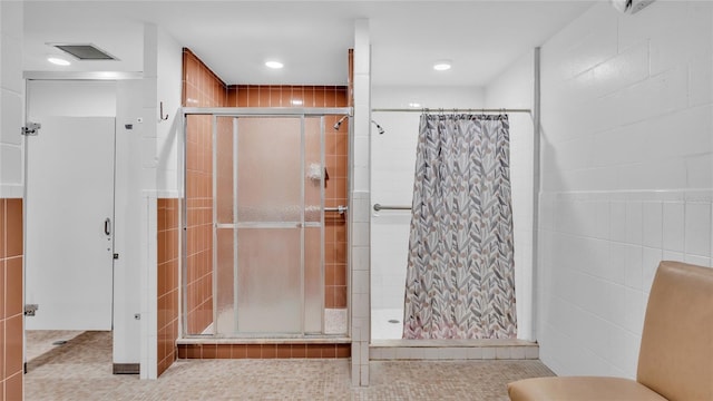 bathroom featuring a shower with shower curtain, tile patterned flooring, and tile walls