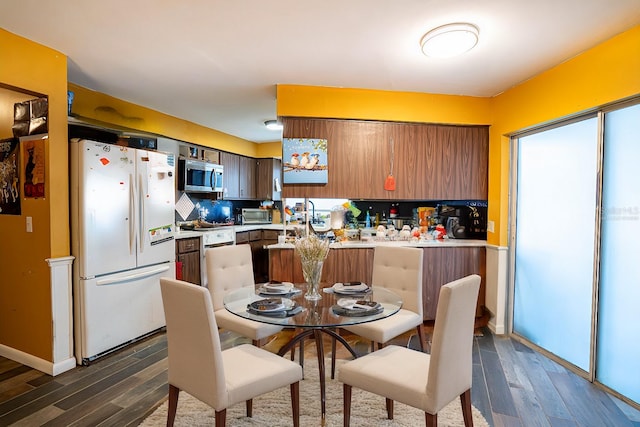 kitchen with dark hardwood / wood-style flooring, white appliances, and backsplash