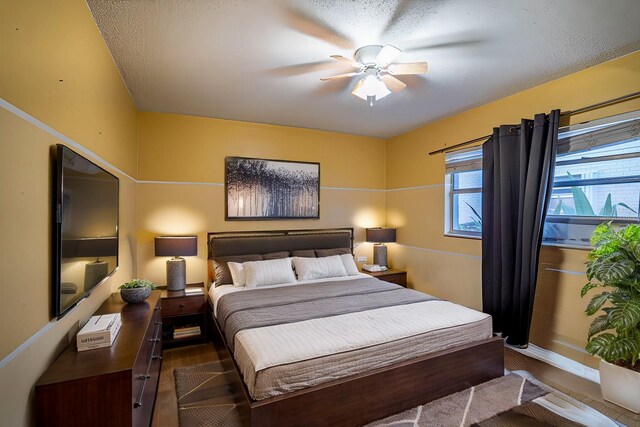 bedroom featuring ceiling fan, dark hardwood / wood-style floors, and a textured ceiling