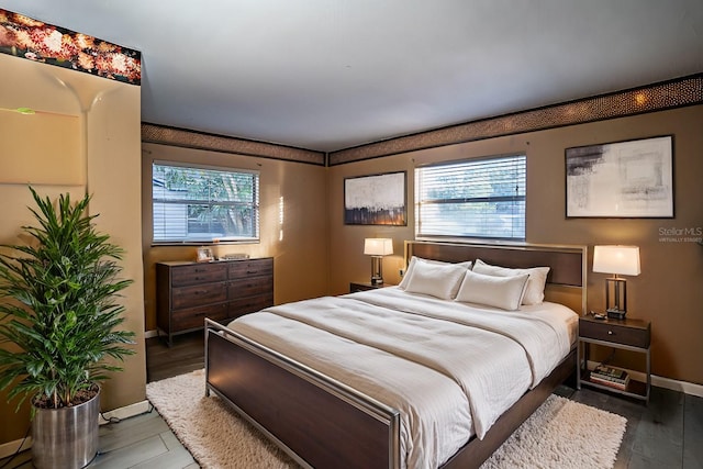 bedroom with multiple windows and dark wood-type flooring